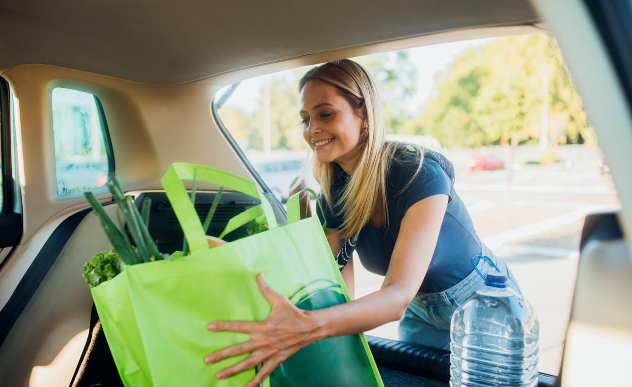 woman packing shopping bags full of groceries into the car trunk